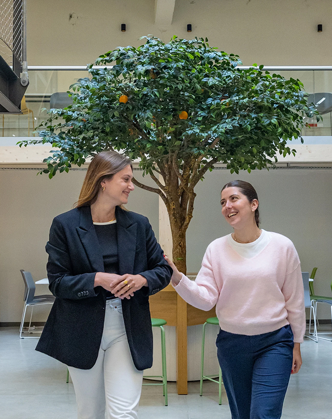 Smiling students from the ECE business school in front of the orange tree in the hall of the Rennes campus