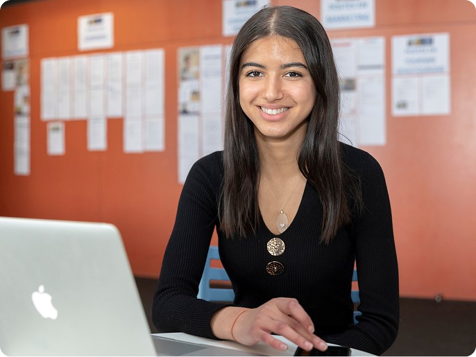 Étudiante souriante devant un ordinateur