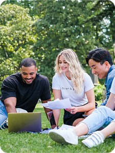Étudiants travaillant devant un ordinateur sur l'herbe